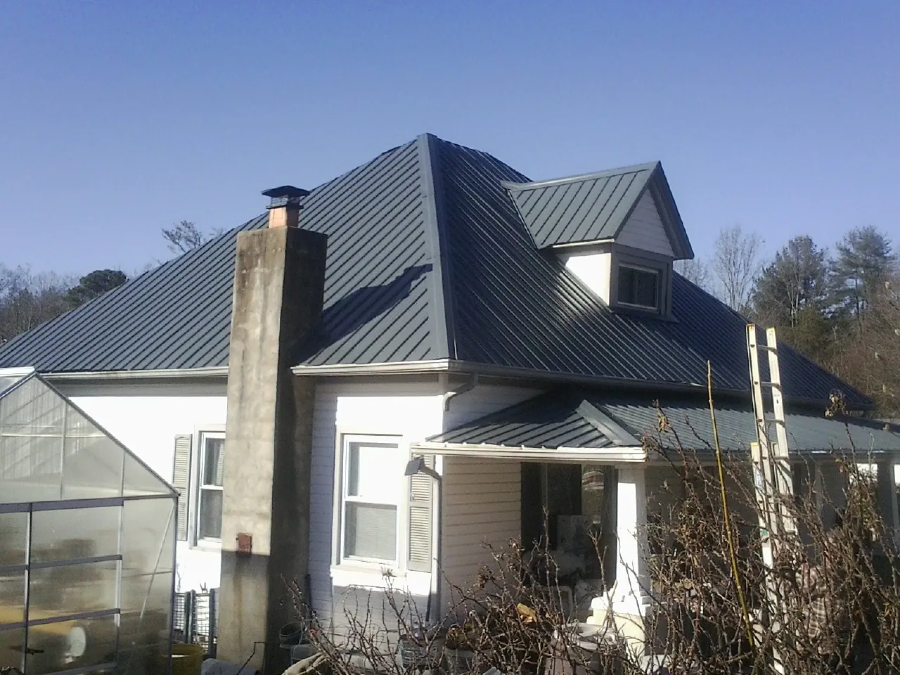 Dark blue standing seam metal roof on a white farmhouse with dormer — Slate & Tile Roof Repair by Roofing Brothers in Vandalia