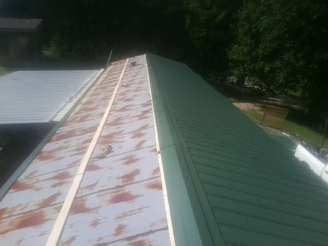 Old rusted panels beside newly installed green metal roofing — Wind Damage Roof Repair by Roofing Brothers in Vandalia